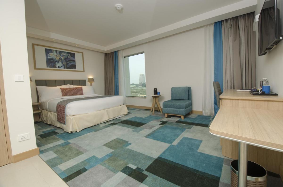 a hotel room with a bed and a chair at Holiday Inn Bengaluru Racecourse by IHG in Bengaluru a hotel room with a bed and a chair at Holiday Inn Bengaluru Racecourse by IHG in Bengaluru