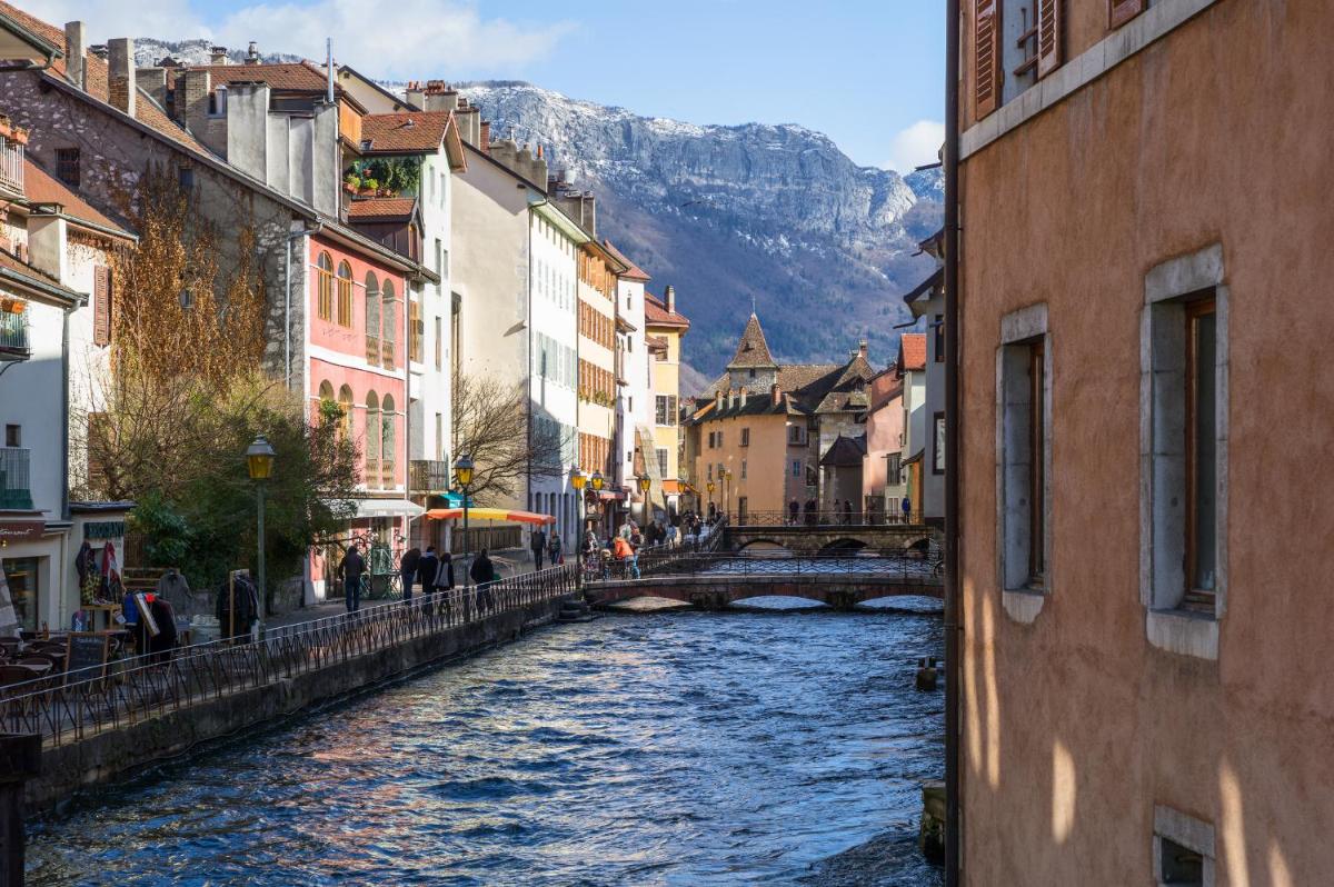 une rivière dans une ville avec un pont et des montagnes dans l'établissement Les Loges Annecy Vieille Ville, à Annecy