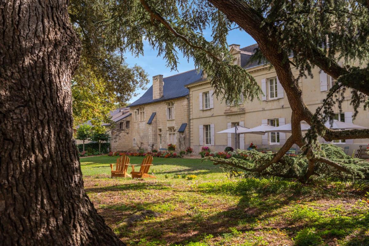 une grande maison avec des chaises et un arbre dans l'établissement Le Domaine de Mestré, The Originals Relais, à Fontevraud-l'Abbaye
