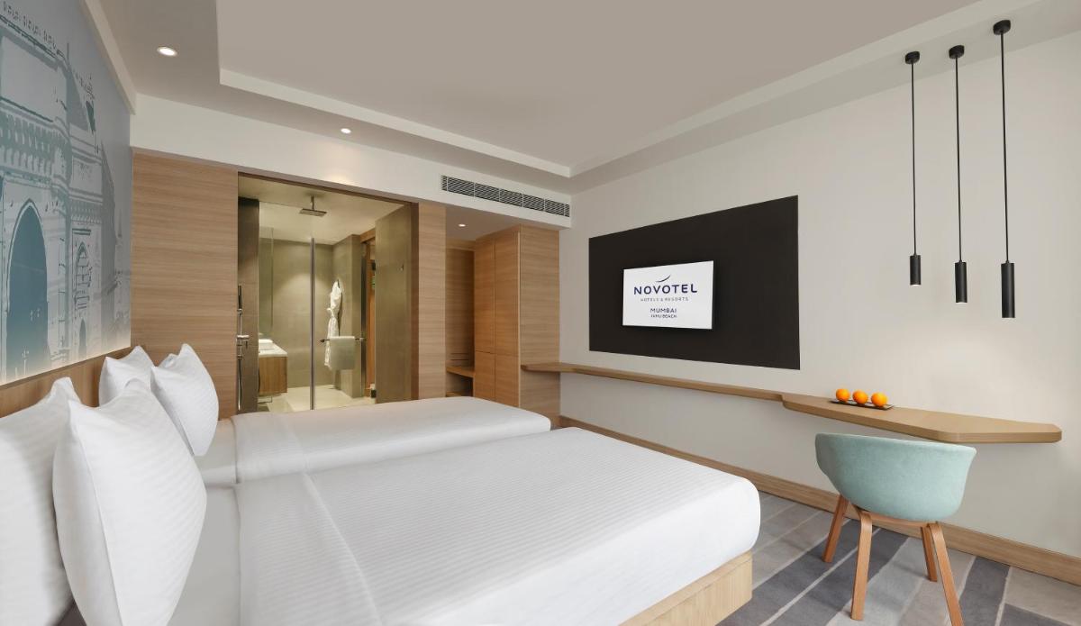 a bedroom with a white bed and a blue chair at Novotel Mumbai Juhu Beach in Mumbai