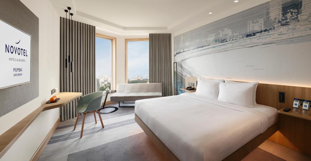 a hotel room with a large bed and a desk at Novotel Mumbai Juhu Beach in Mumbai