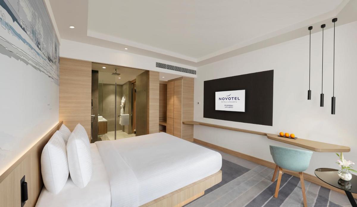 a bedroom with a bed and a desk and a television at Novotel Mumbai Juhu Beach in Mumbai