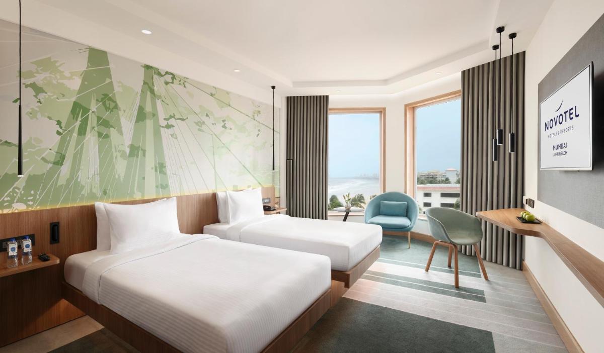 a hotel room with two beds and a desk at Novotel Mumbai Juhu Beach in Mumbai