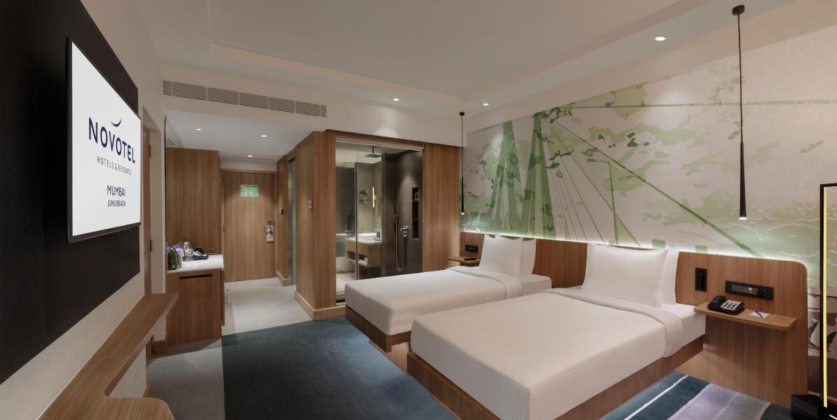 a hotel room with a bed and a bathroom at Novotel Mumbai Juhu Beach in Mumbai