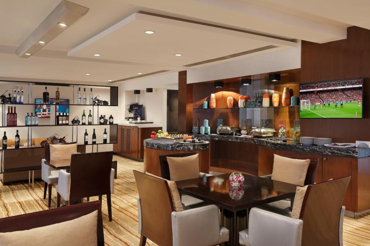 a restaurant with a bar with tables and chairs at Novotel Mumbai Juhu Beach in Mumbai