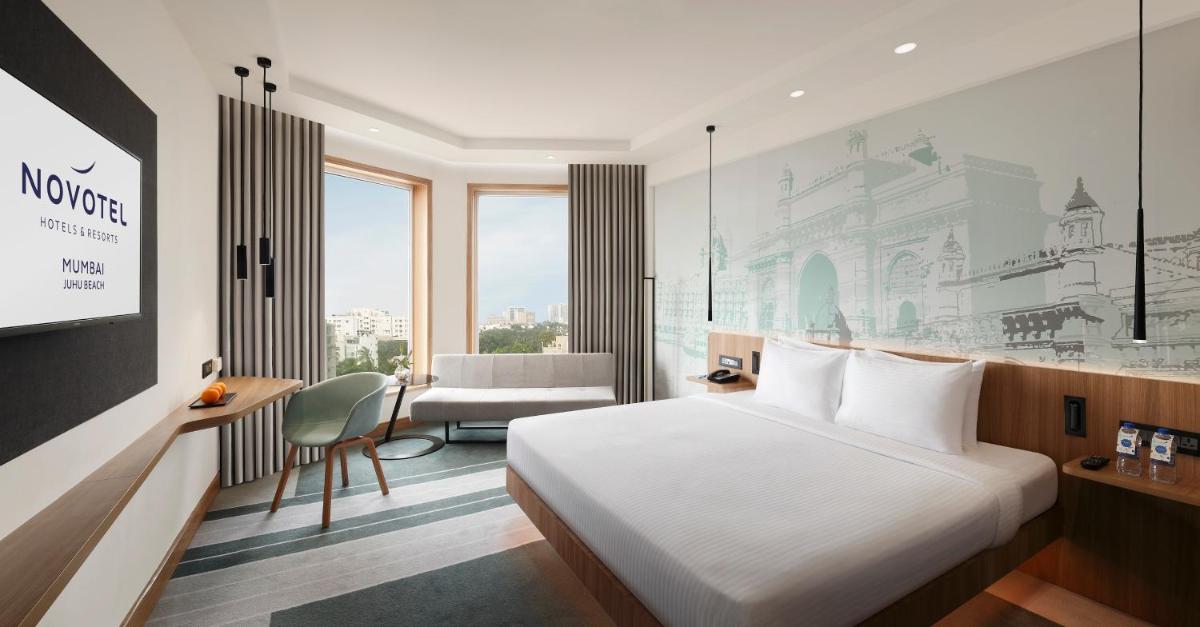 a hotel room with a bed and a desk and a chair at Novotel Mumbai Juhu Beach in Mumbai