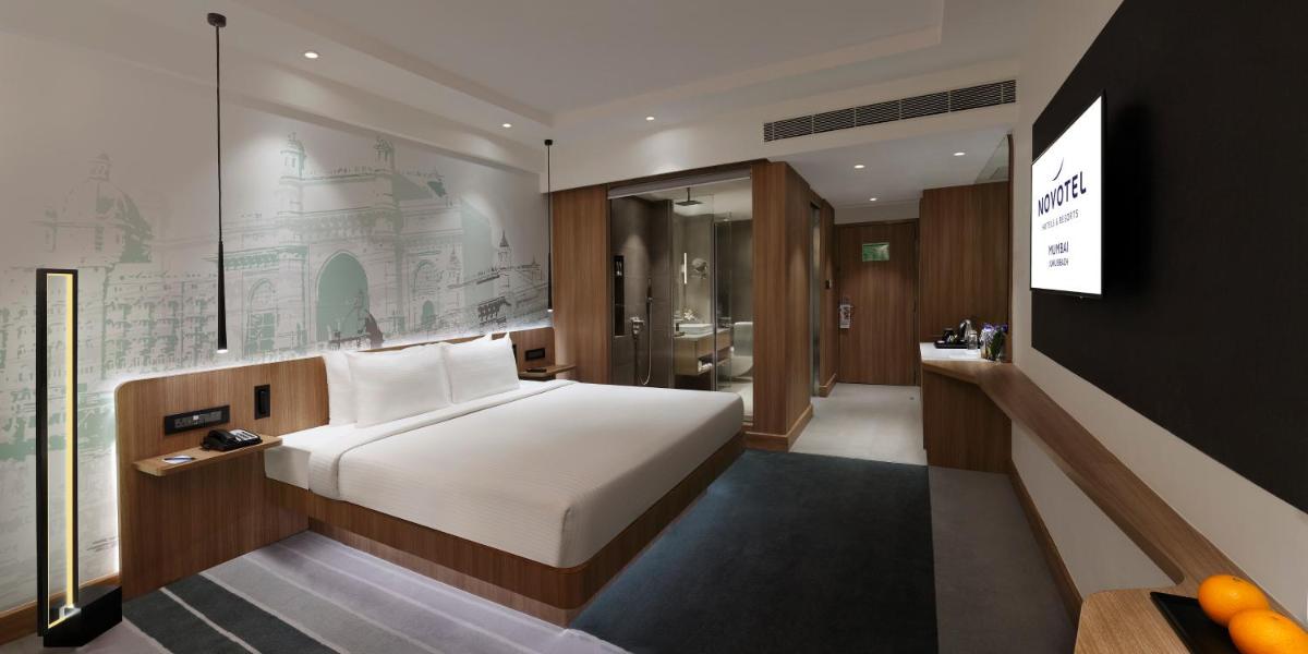 a hotel room with a bed and a bathroom at Novotel Mumbai Juhu Beach in Mumbai