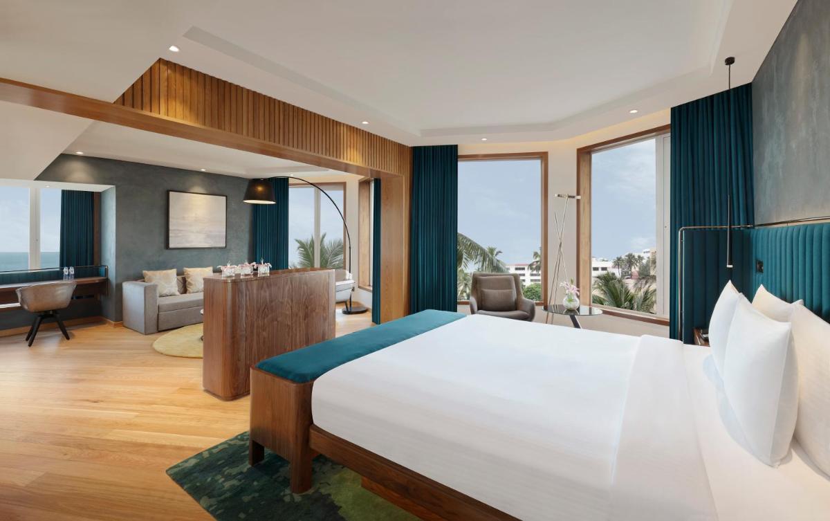 a bedroom with a large bed and a living room at Novotel Mumbai Juhu Beach in Mumbai