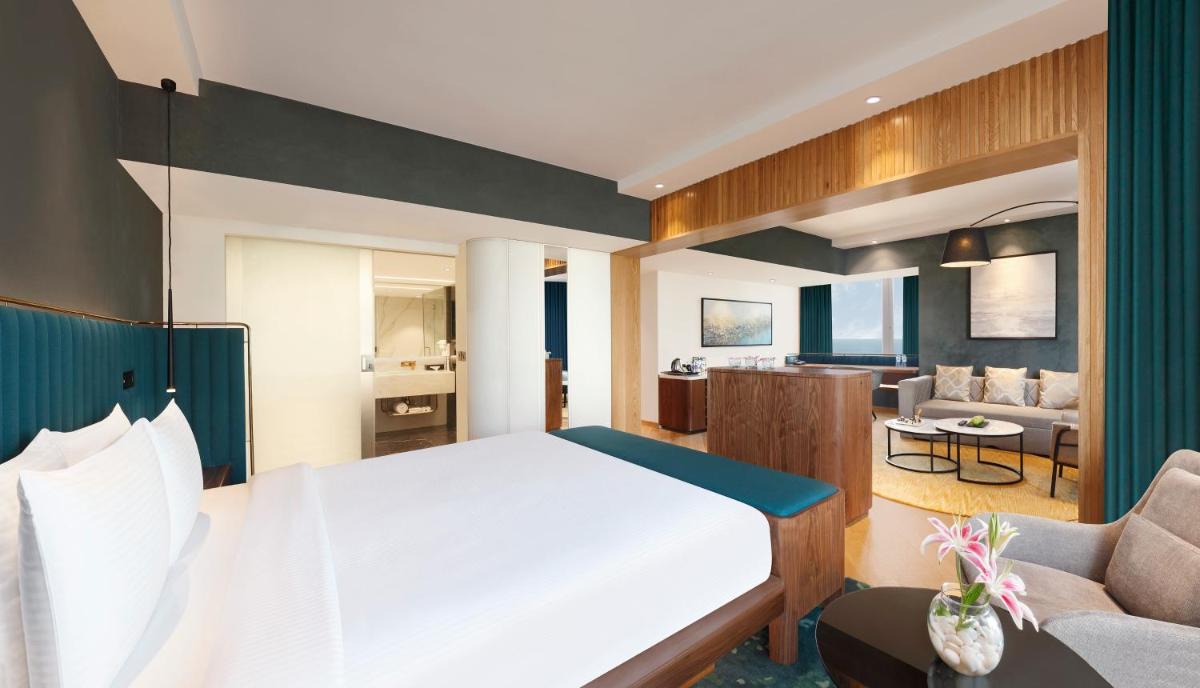 a bedroom with a large bed and a living room at Novotel Mumbai Juhu Beach in Mumbai