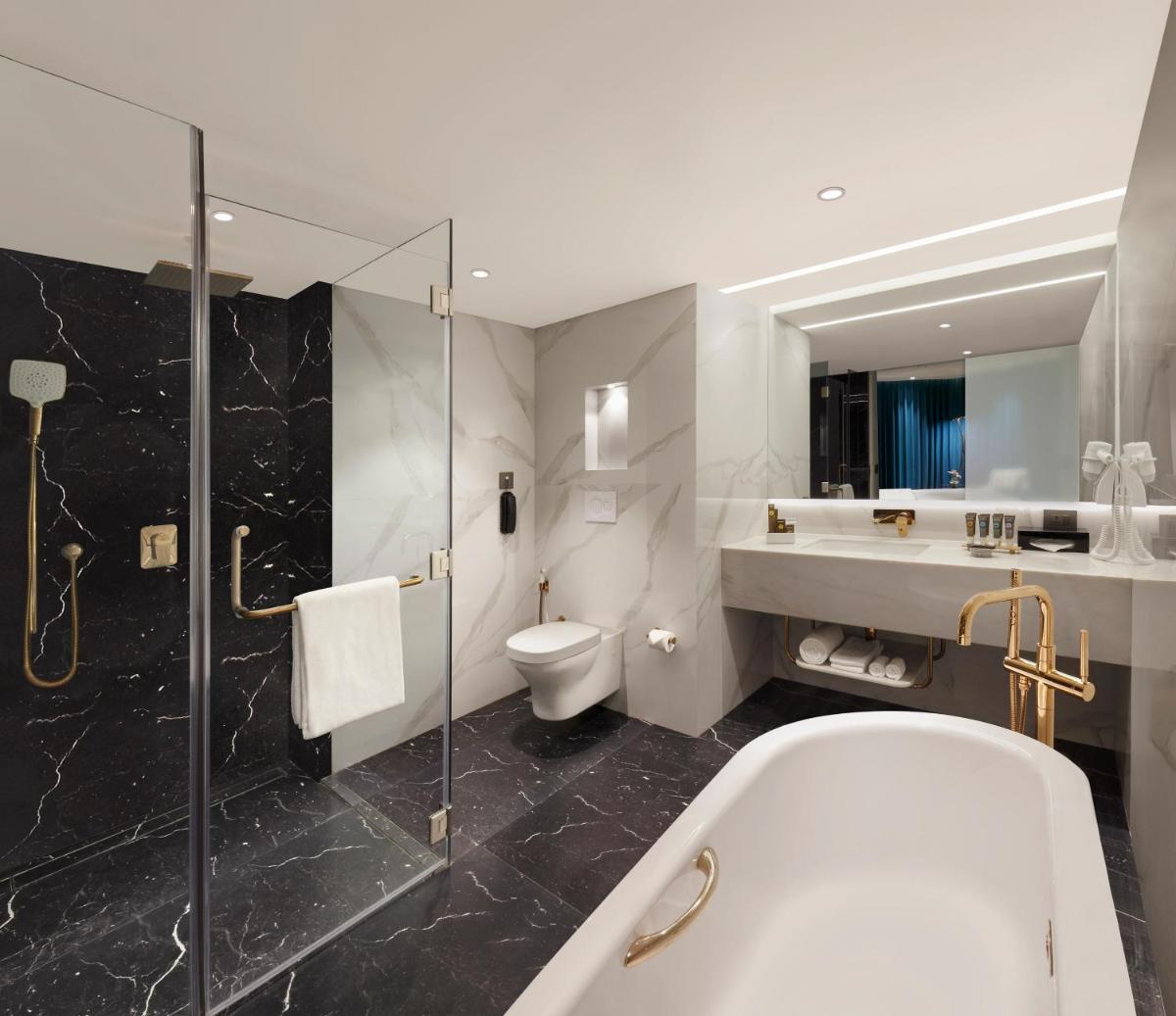 a bathroom with a tub and a sink and a toilet at Novotel Mumbai Juhu Beach in Mumbai