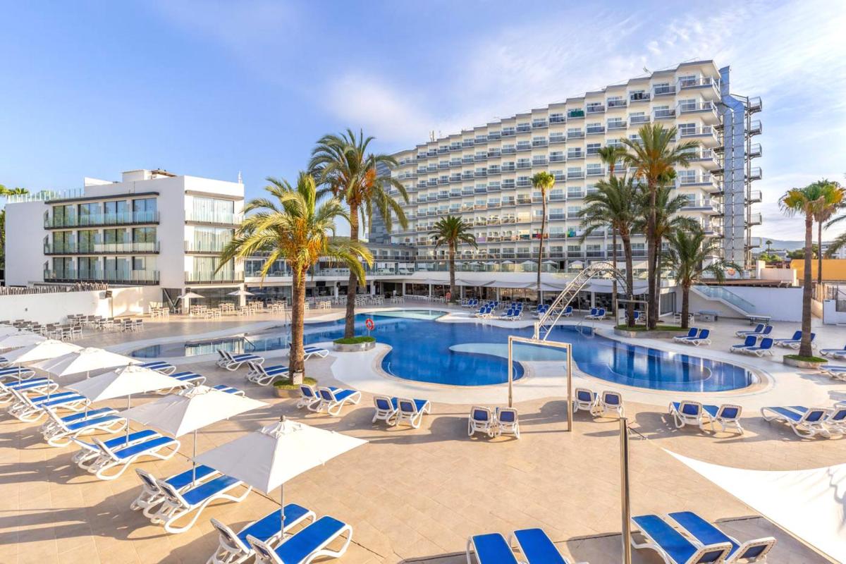 Una piscina con tumbonas y un hotel. en Hotel Samos, en Magaluf