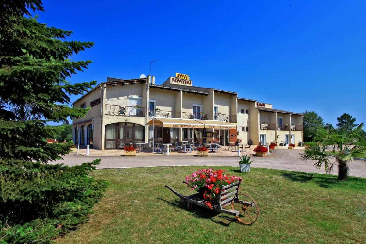 un bâtiment avec un banc fleuri devant dans l'établissement Logis Hotel Le Tropicana, à Douville