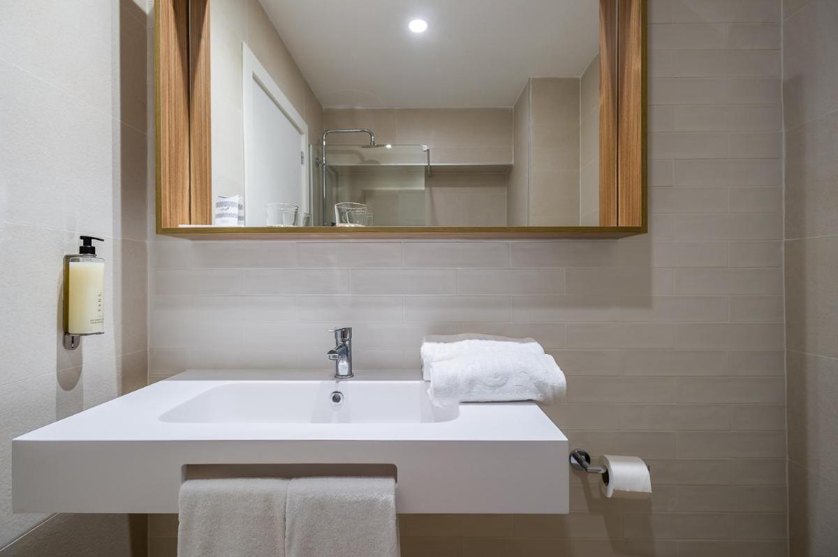 Un baño con lavabo, espejo y toallas. en Intelier Orange, en Benicàssim