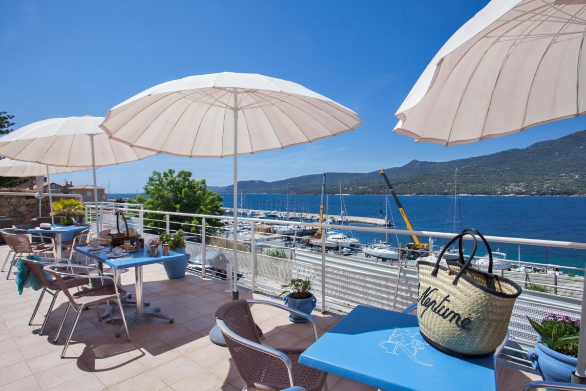 d'une terrasse avec des tables et des parasols offrant une vue sur l'eau. dans l'établissement Le Neptune & Spa, à Propriano