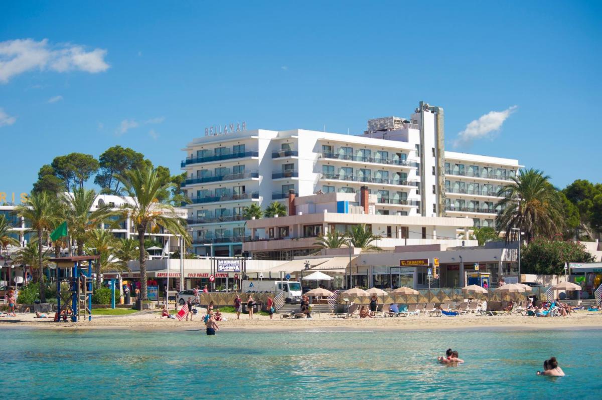 personas en el agua en una playa con un gran edificio en Bellamar Hotel Beach & Spa, en San Antonio