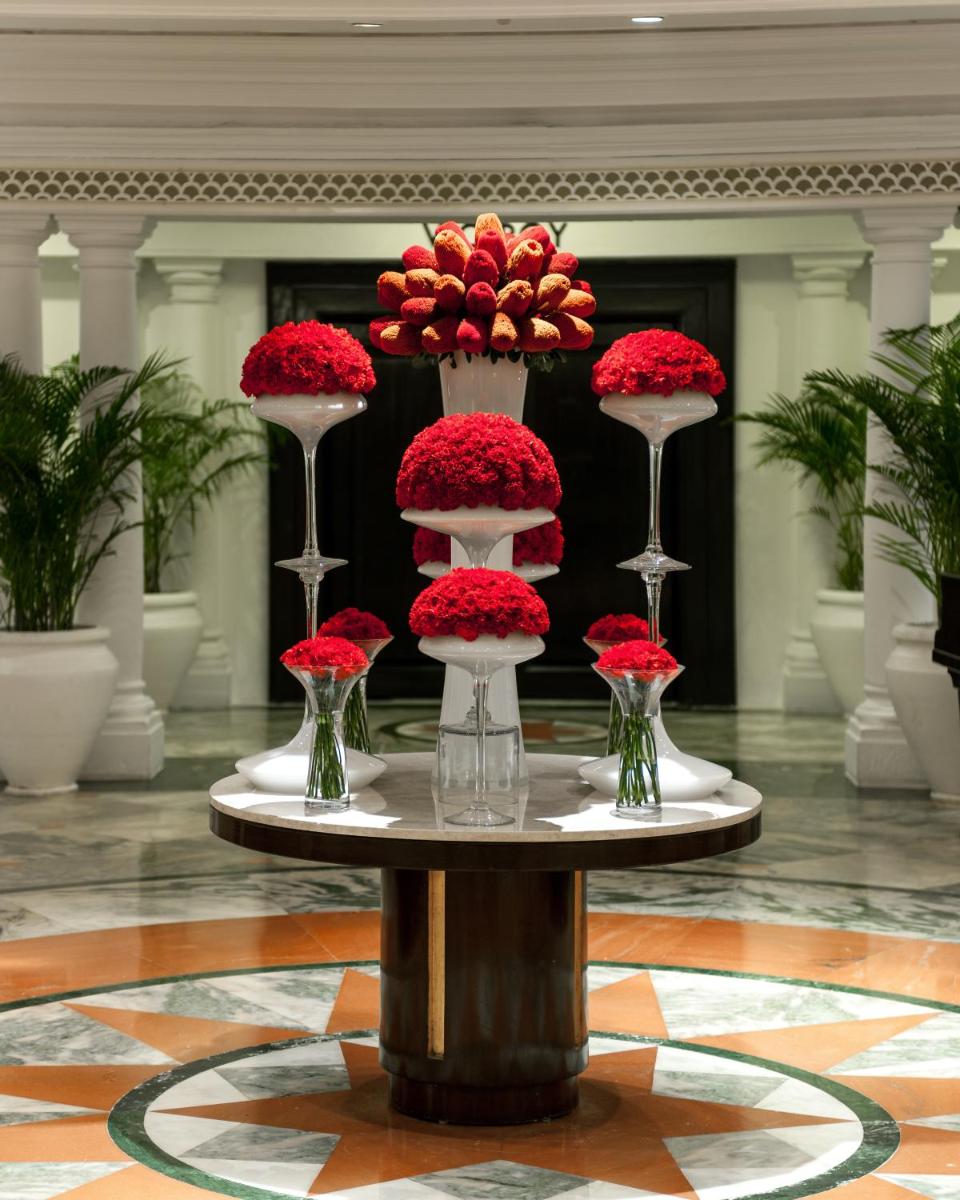a table with red flowers and vases on it at The Claridges New Delhi in New Delhi a table with red flowers and vases on it at The Claridges New Delhi in New Delhi