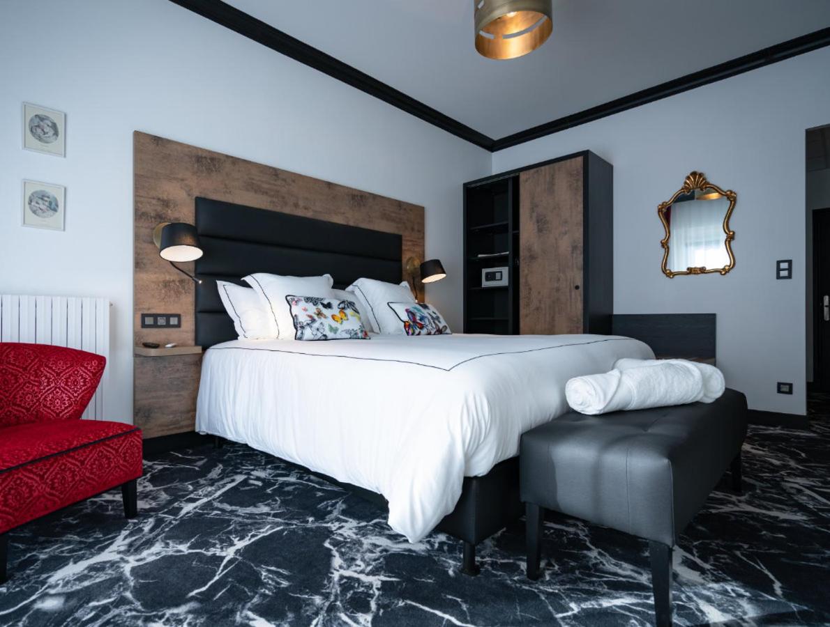 une chambre avec un grand lit et une chaise rouge dans l'établissement Hôtel du Barry Resort & Spa, à Sauveterre