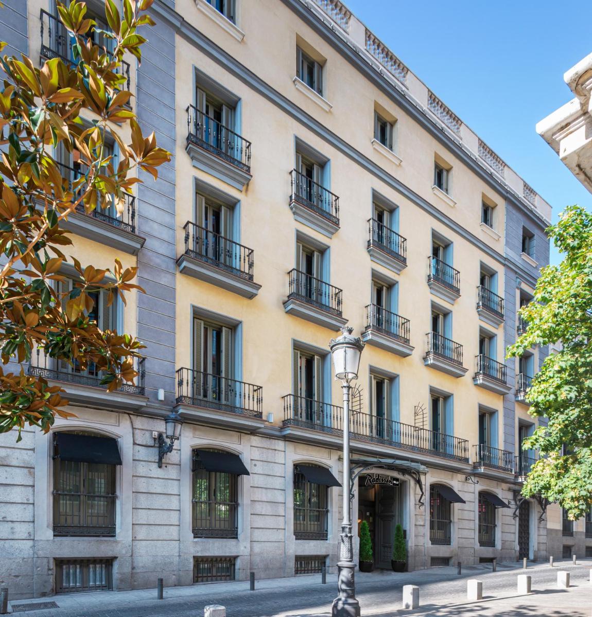 un gran edificio con balcones y luz de la calle en Radisson Blu Hotel, Madrid Prado, en Madrid