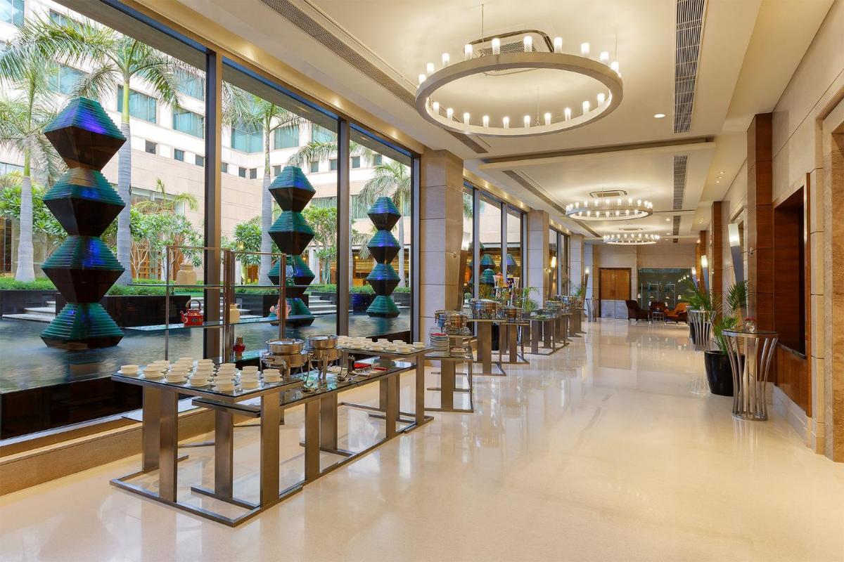 a lobby with a row of tables in a building at Crowne Plaza Today Gurugram by IHG in Gurgaon
