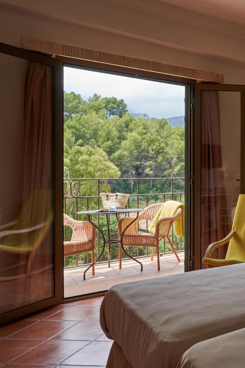 Habitación con cama y balcón con mesa y sillas. en Hotel Es Port, en Puerto de Sóller 81 fotos más