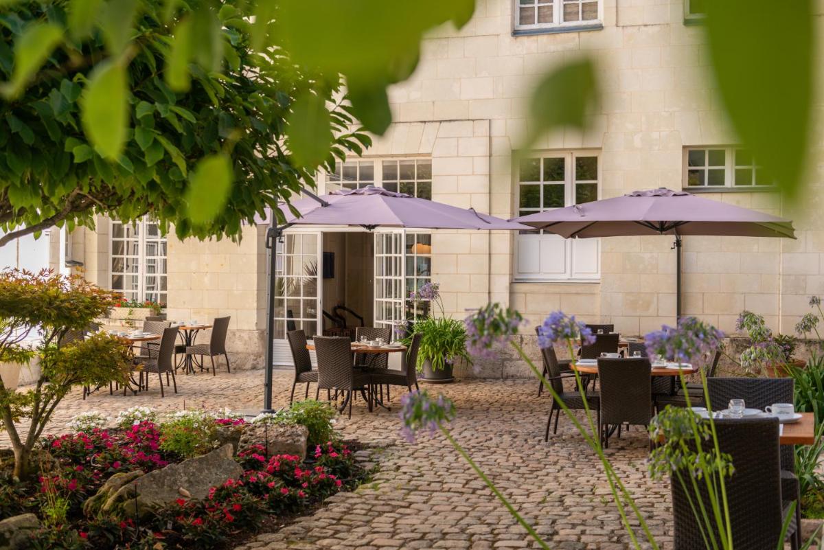 un patio avec des tables et des parasols devant un bâtiment dans l'établissement Hôtel Anne d'Anjou, The Originals Collection, à Saumur