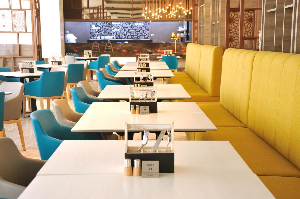 a restaurant with white tables and blue chairs at Holiday Inn Gurugram Sector 90 by IHG in Gurgaon
