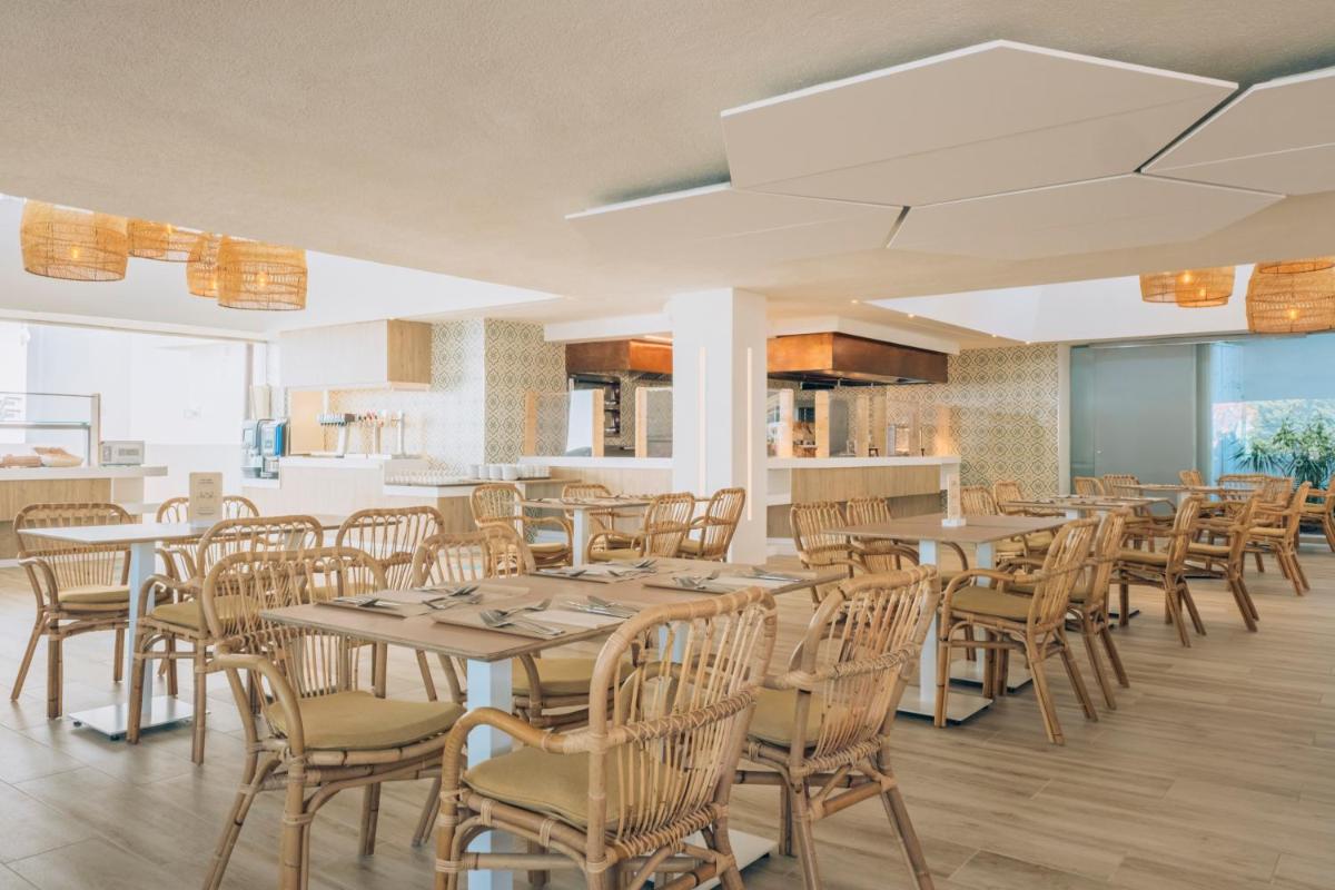 Un comedor con mesas y sillas de madera. en Iberostar Waves Royal Andalus, en Chiclana de la Frontera