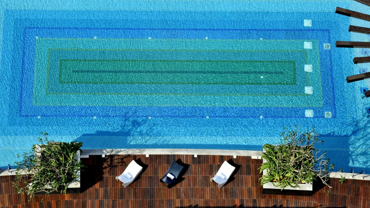 a swimming pool with two chairs next to a swimming pool at The Oterra in Bengaluru