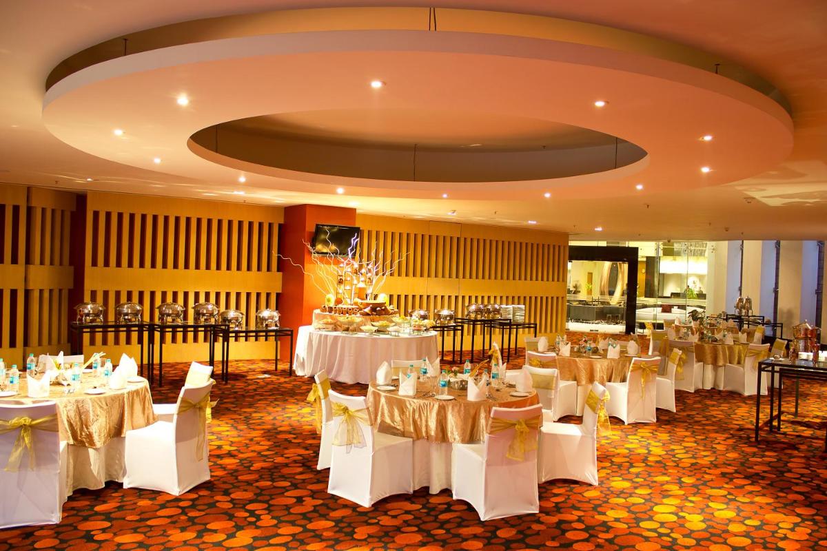 a banquet hall with white tables and white chairs at The Oterra in Bengaluru