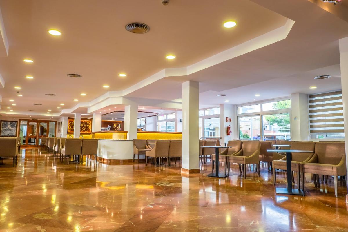 Un restaurante con mesas y sillas en un edificio. en Sagitario Playa, en Cala Blanca