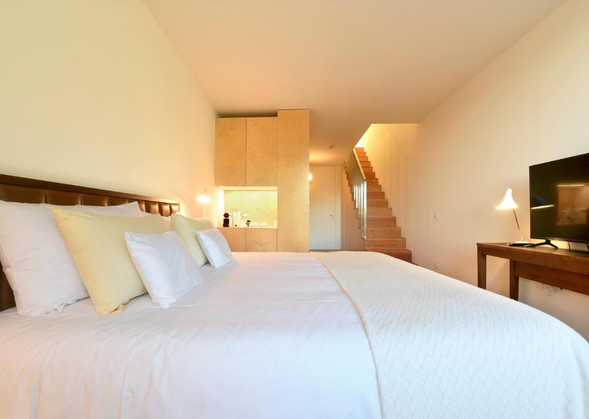 um quarto com uma grande cama branca e uma televisão em Casas Da Lapa, Nature & Spa Hotel em Seia