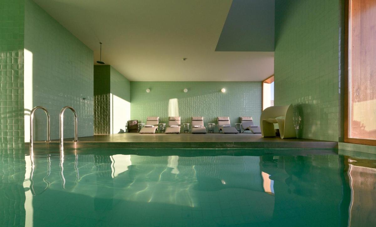 uma piscina com um monte de cadeiras em uma sala em Casas Da Lapa, Nature & Spa Hotel em Seia uma piscina com um monte de cadeiras em uma sala em Casas Da Lapa, Nature & Spa Hotel em Seia