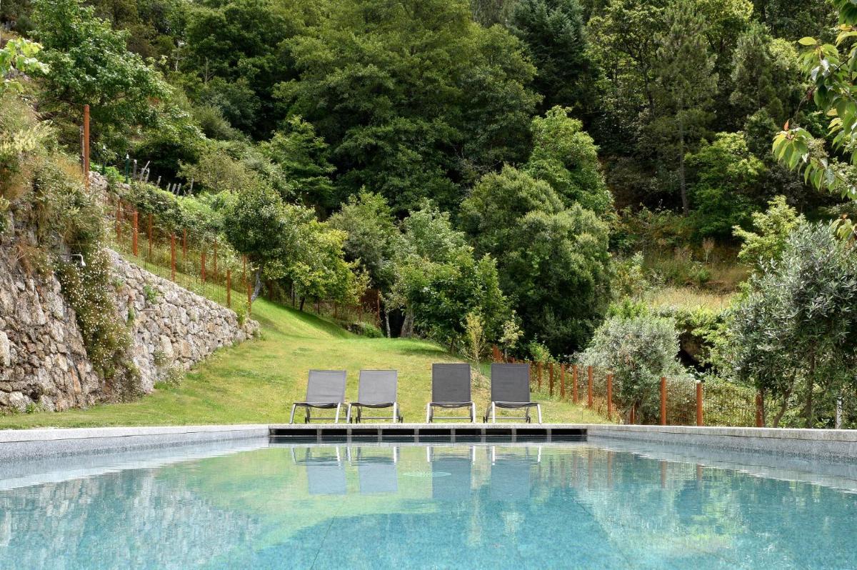 duas espreguiçadeiras ao lado de uma piscina em Casas Da Lapa, Nature & Spa Hotel em Seia duas espreguiçadeiras ao lado de uma piscina em Casas Da Lapa, Nature & Spa Hotel em Seia