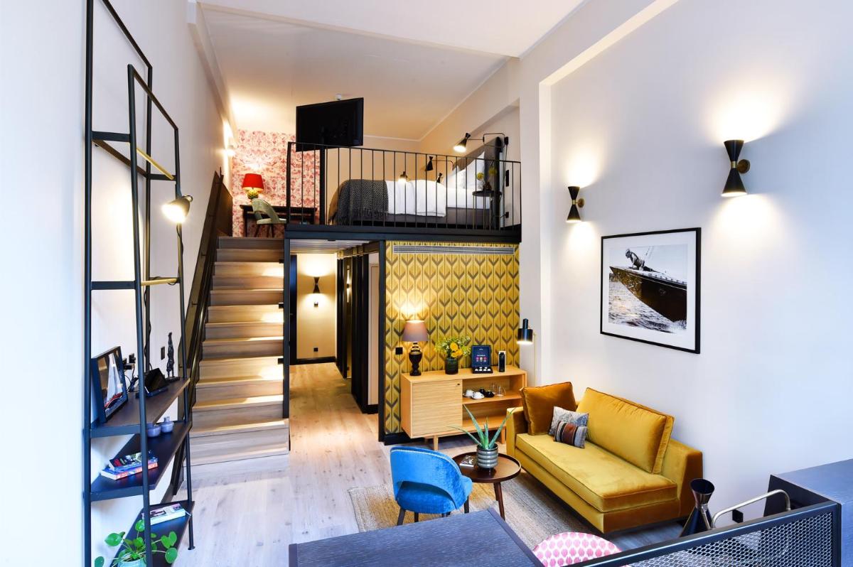 ein Wohnzimmer mit einem gelben Sofa und einer Treppe in der Unterkunft Das James in Flensburg