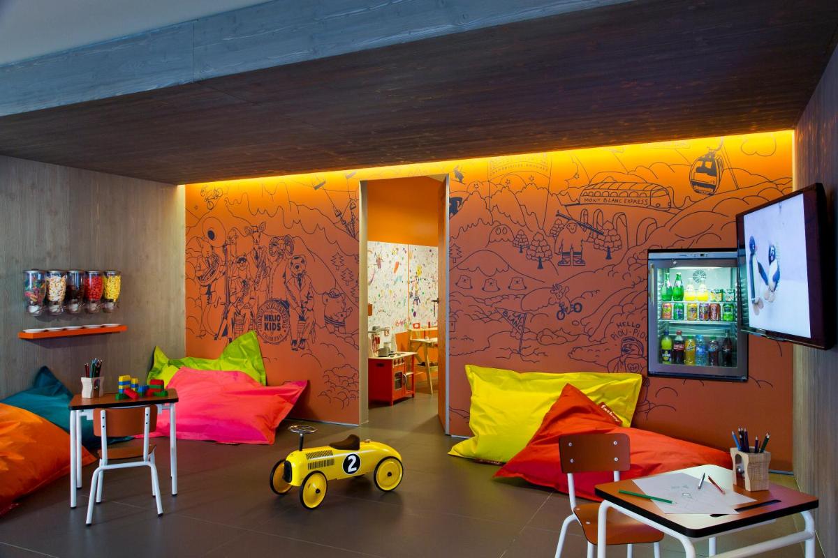 une pièce avec des chaises colorées et un mur avec une télévision dans l'établissement Heliopic Hotel & Spa, à Chamonix-Mont-Blanc