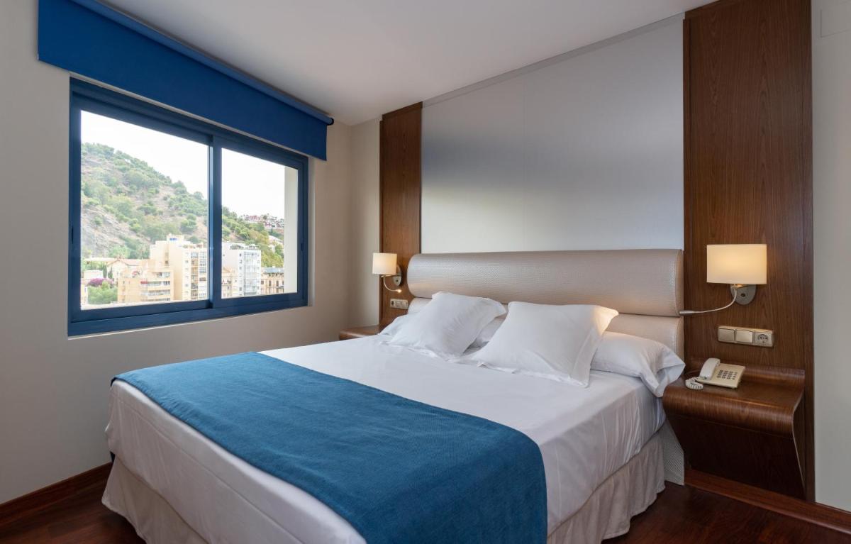 Un dormitorio con una cama grande y una ventana. en Hotel MS Maestranza Málaga, en Málaga