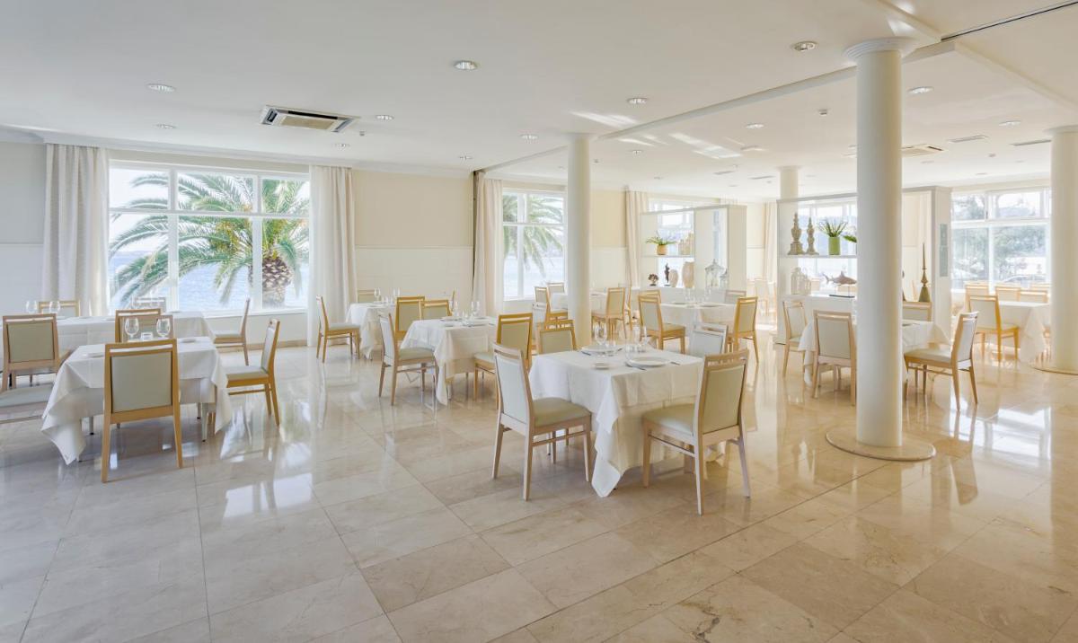 Un comedor con mesas y sillas blancas. en Eurostars Louxo Talaso, en Isla de la Toja