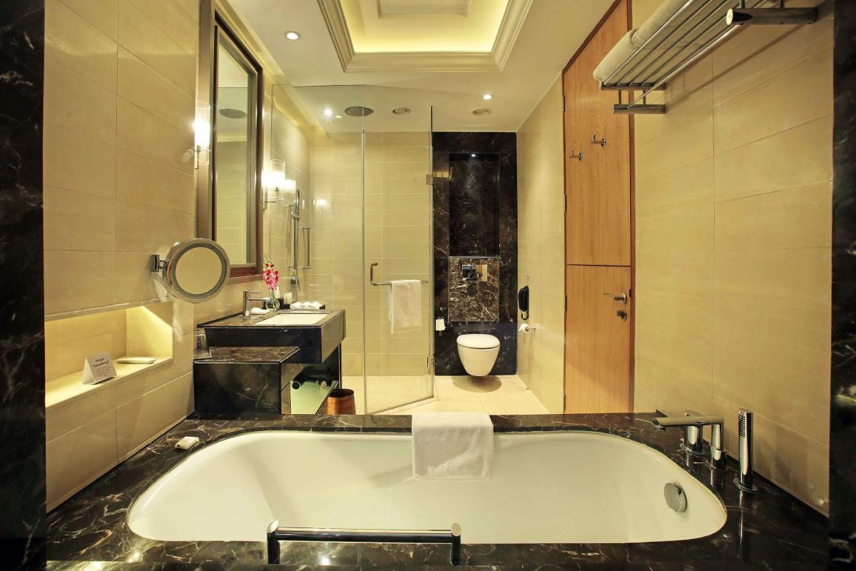 a bathroom with a tub and a sink and a toilet at Crowne Plaza New Delhi Mayur Vihar Noida by IHG in New Delhi