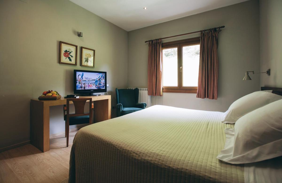 Un dormitorio con una cama y un escritorio con televisión. en Hotel Manantial, en Caldes de Boí