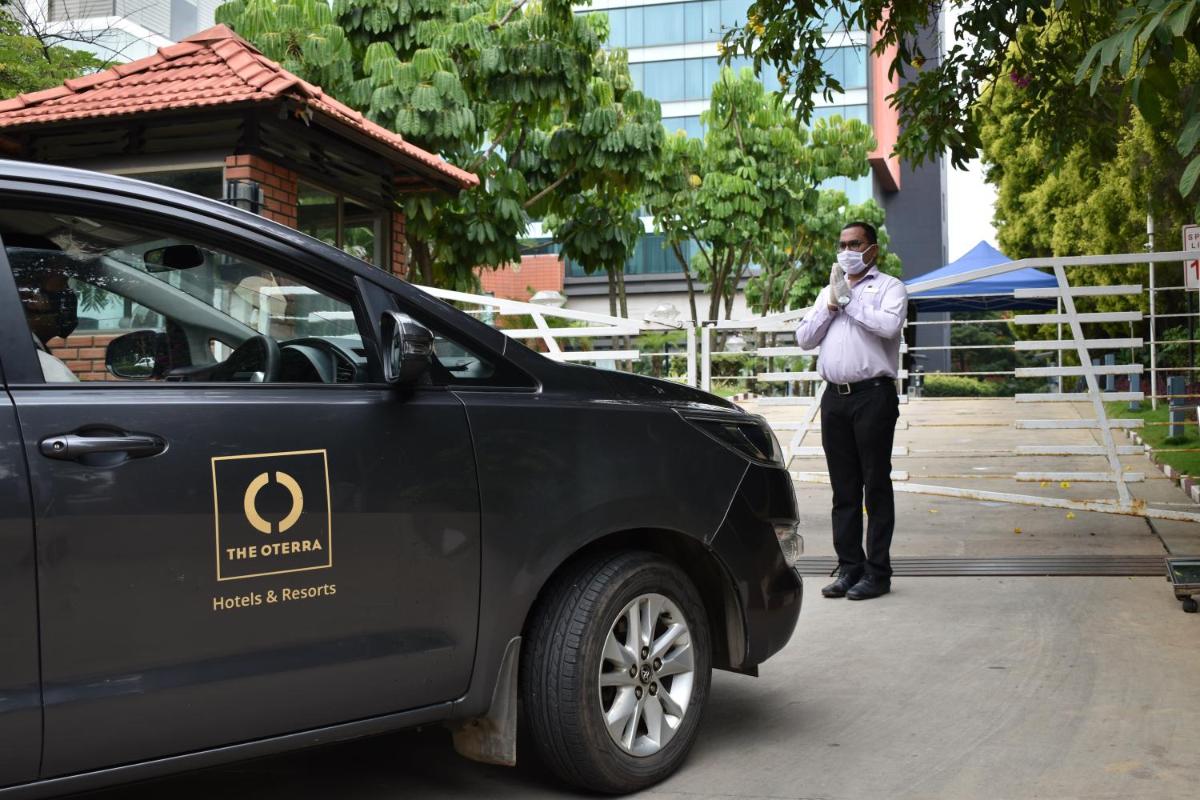 a man wearing a mask standing next to a car at The Oterra in Bengaluru