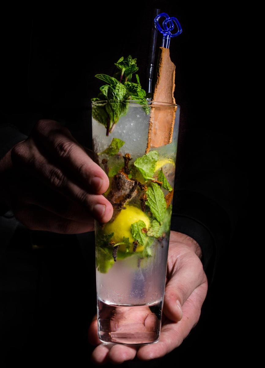 a hand holding a drink with a bottle in it at Sofitel Mumbai BKC in Mumbai