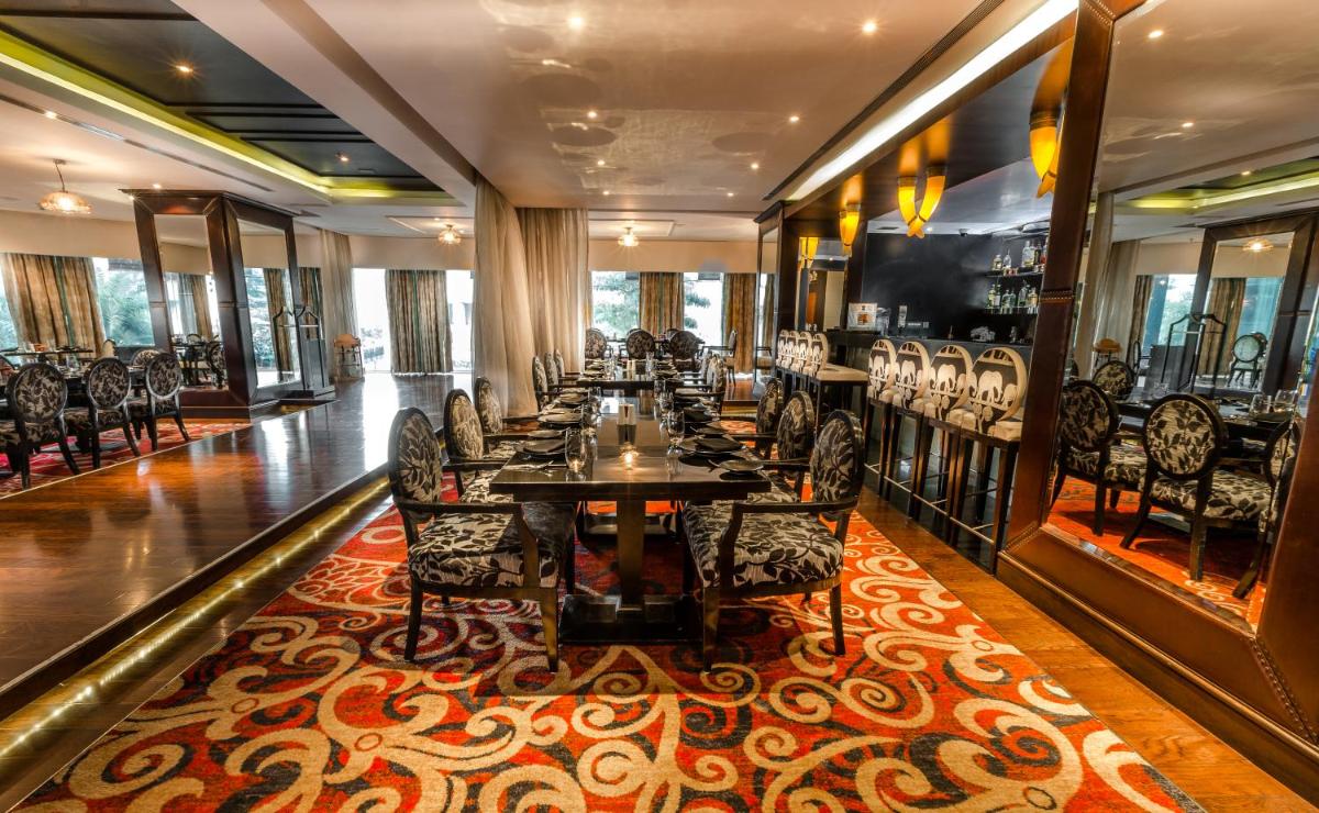 a long dining room with tables and chairs on a rug at Sofitel Mumbai BKC in Mumbai