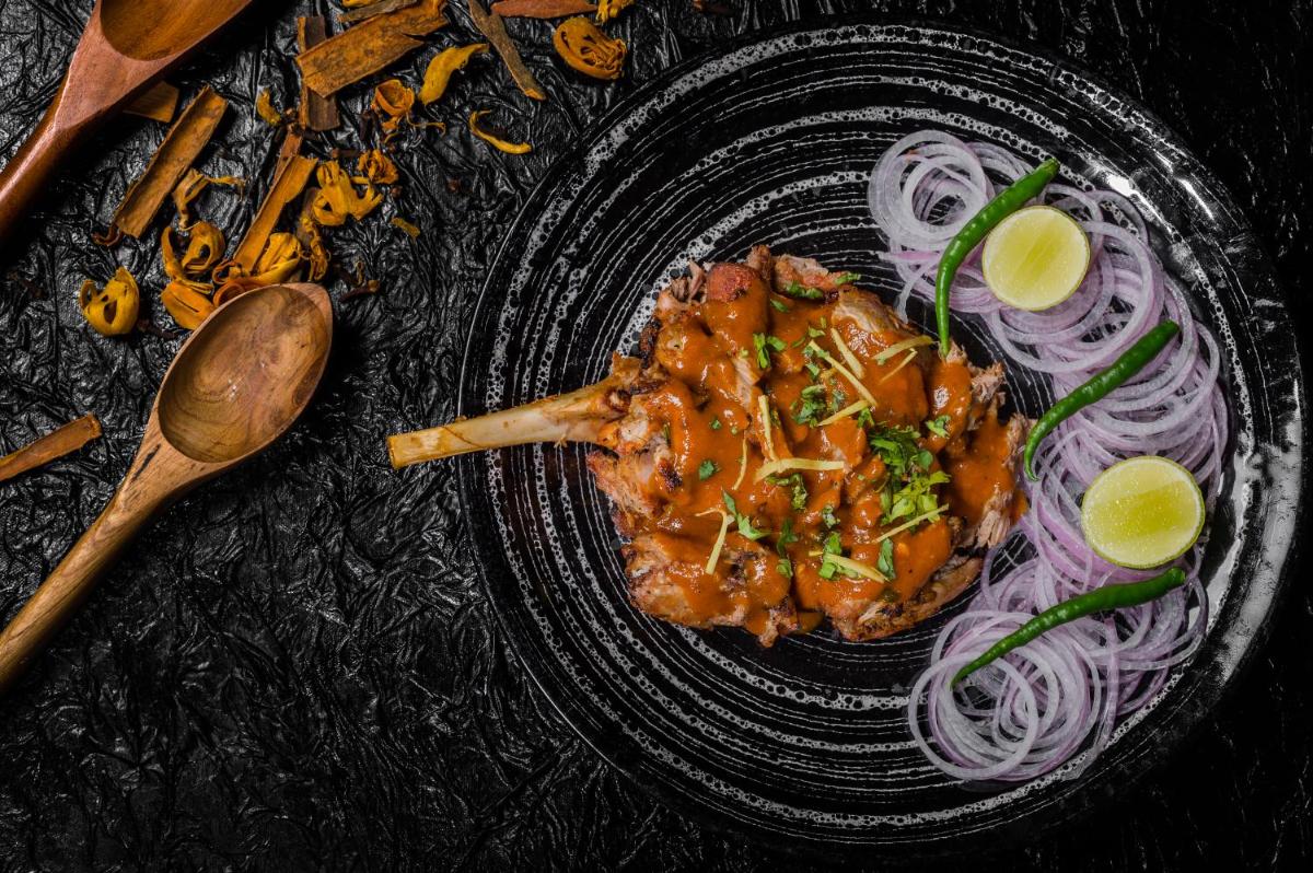 a plate of food with meat and onions on a table at Sofitel Mumbai BKC in Mumbai