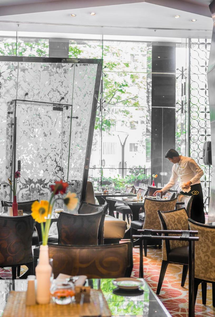 a man standing in a restaurant with tables and chairs at Sofitel Mumbai BKC in Mumbai