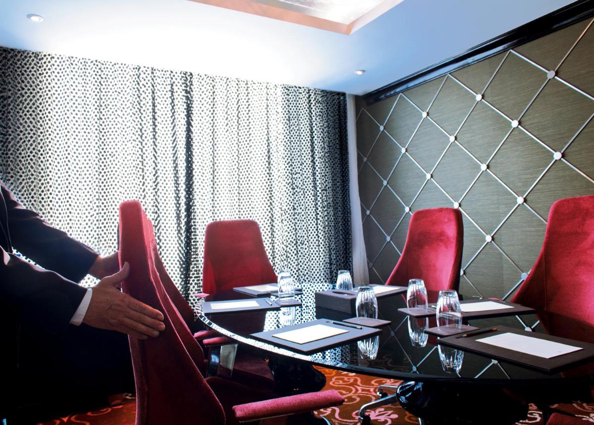a dining room with a table and red chairs at Sofitel Mumbai BKC in Mumbai