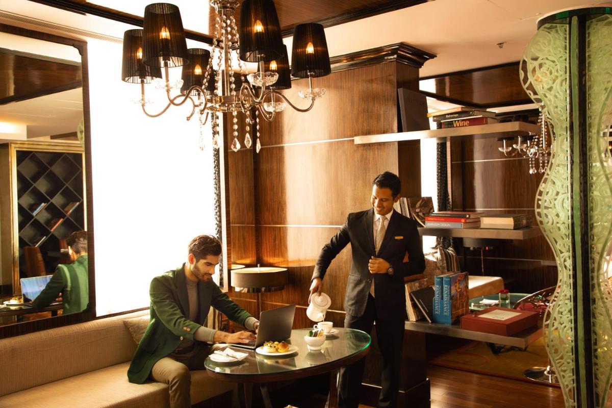 two men in a restaurant with a table with a laptop at Sofitel Mumbai BKC in Mumbai