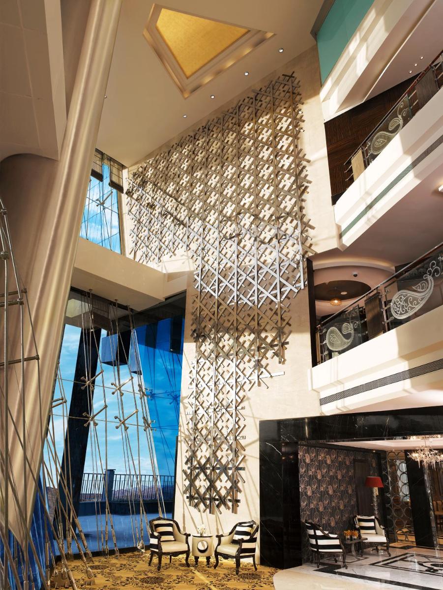 a lobby with chairs and a wall with a large window at Sofitel Mumbai BKC in Mumbai