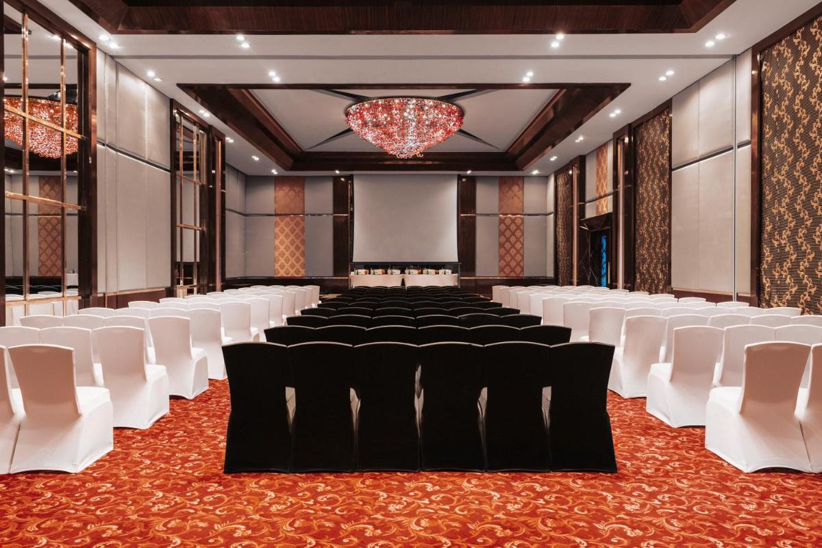 a banquet hall with white chairs and a chandelier at Sofitel Mumbai BKC in Mumbai