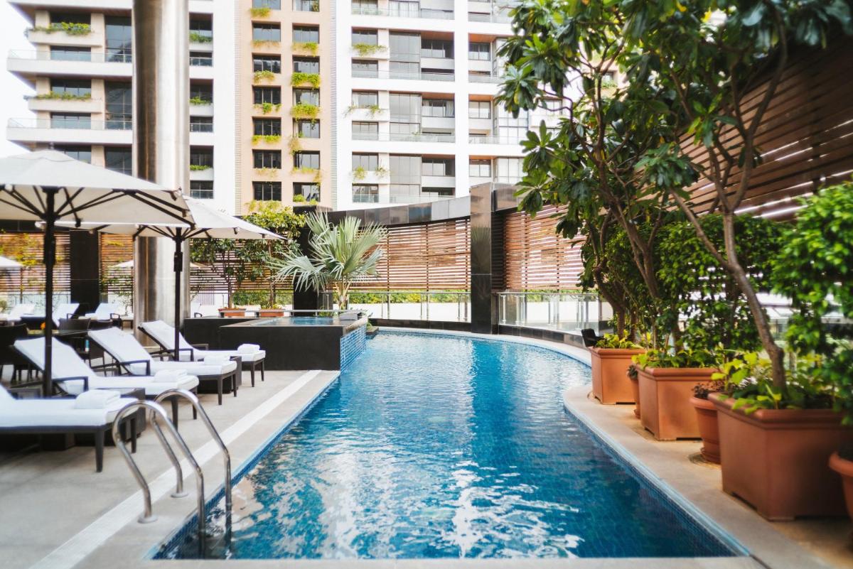 a pool in a building with tables and chairs at Sofitel Mumbai BKC in Mumbai