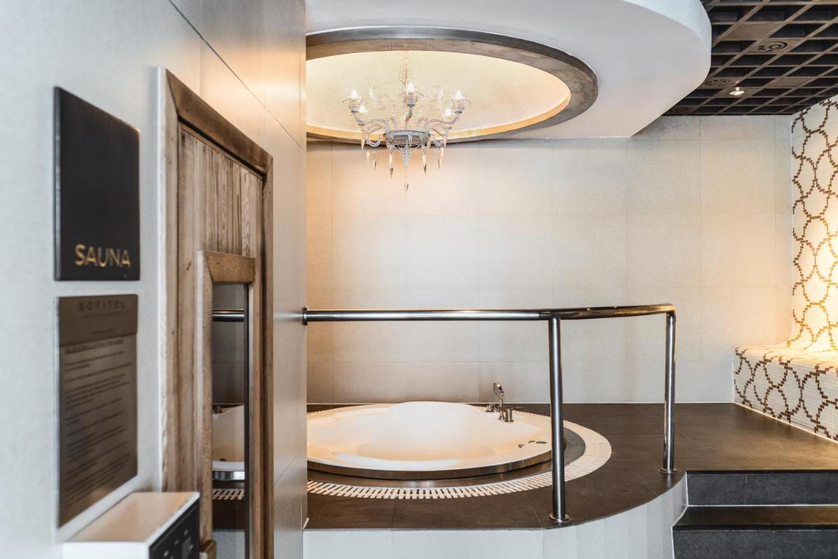 a bath tub in a room with a chandelier at Sofitel Mumbai BKC in Mumbai